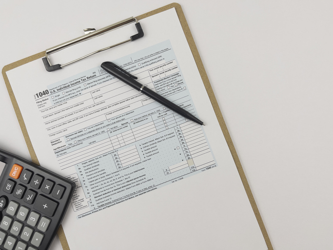 Printed Tax Form on Work Desk with Calculator and Pen.
