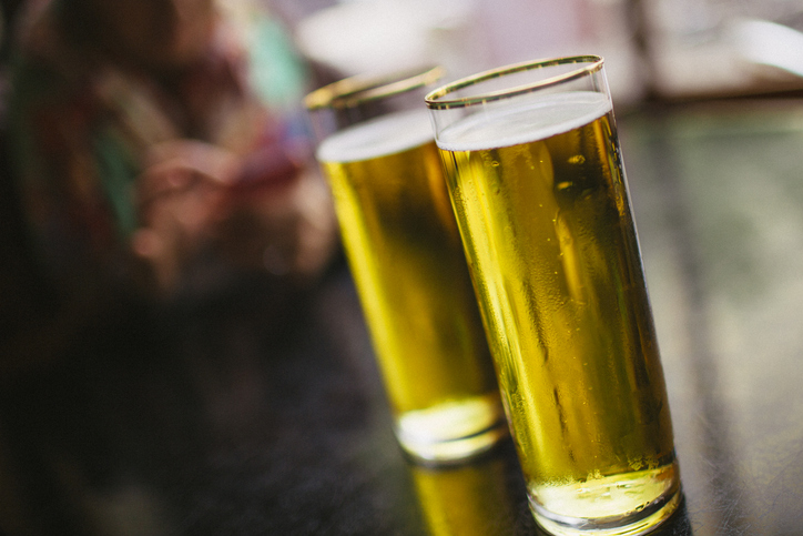 Two refreshing gold rimmed beer glasses on a pub table.