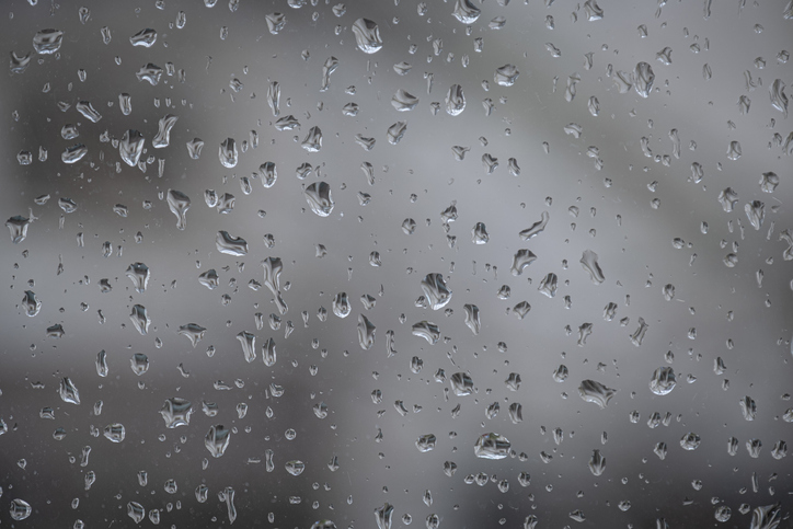Raindrops on window glass surface. Blurred background.