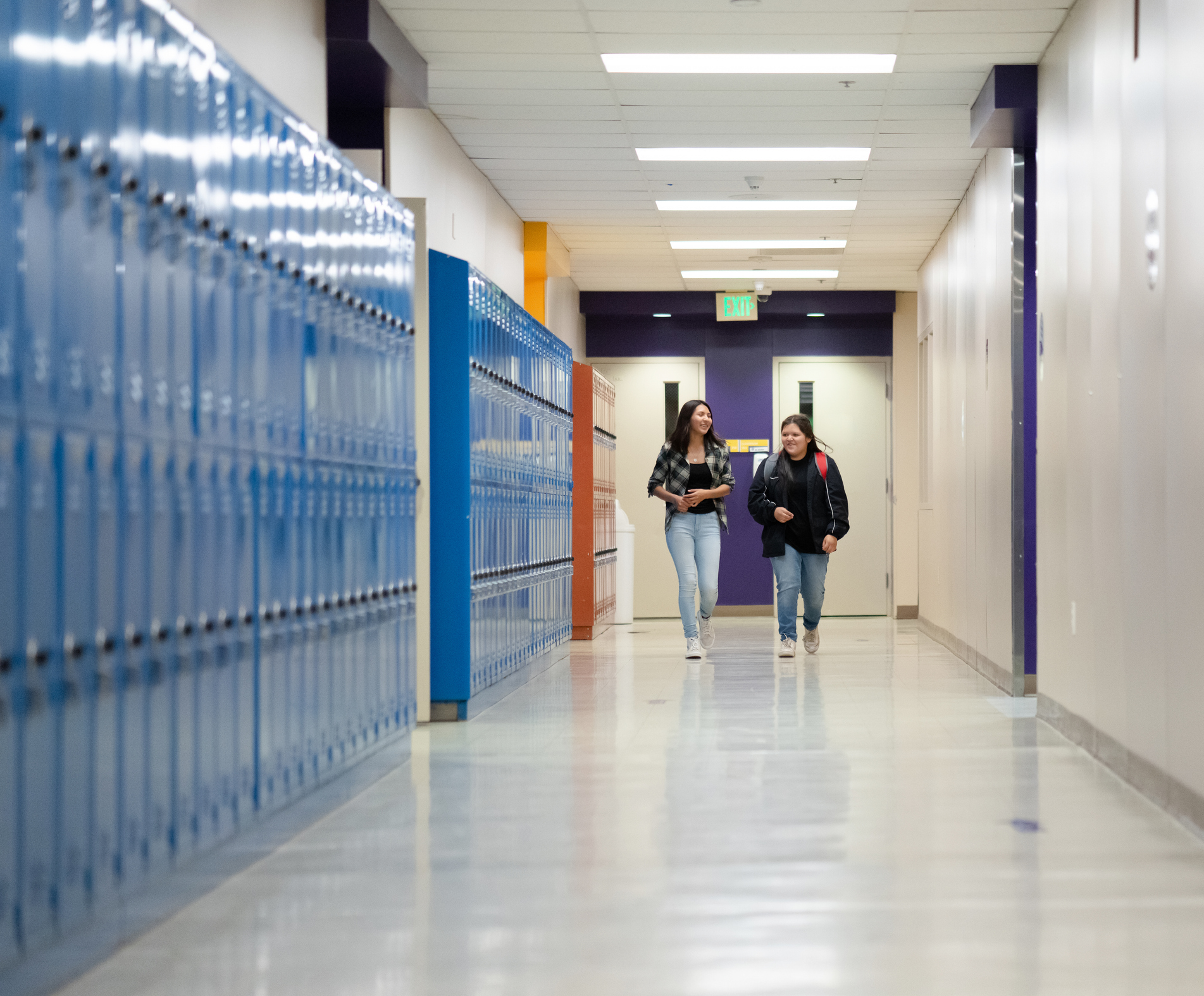 Two female friends at school walking on a corridor
